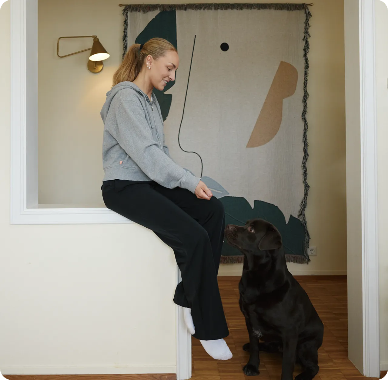 Einstaklingur situr og brosir til hunds