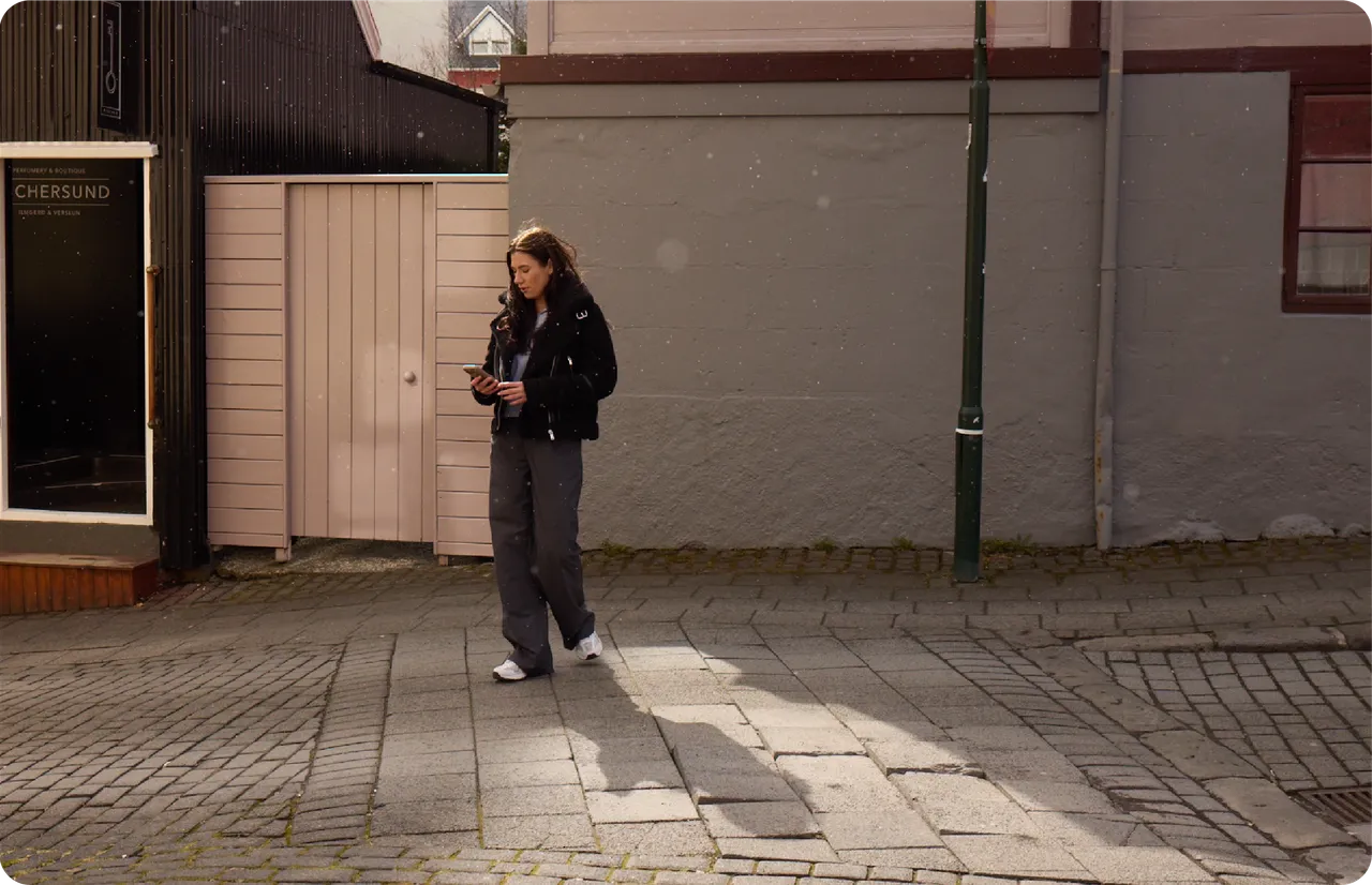 Someone walks along a cobbled street, looking at a phone